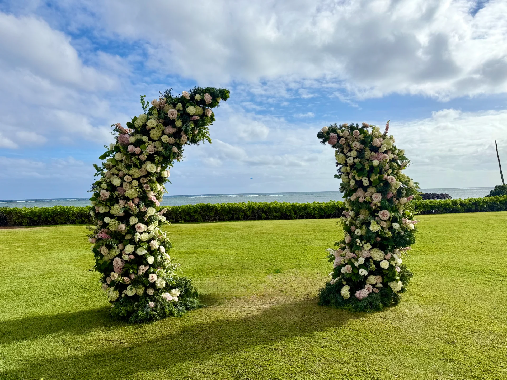 luxurious pink and white floral arch with ocean view on Oʻahu coastline