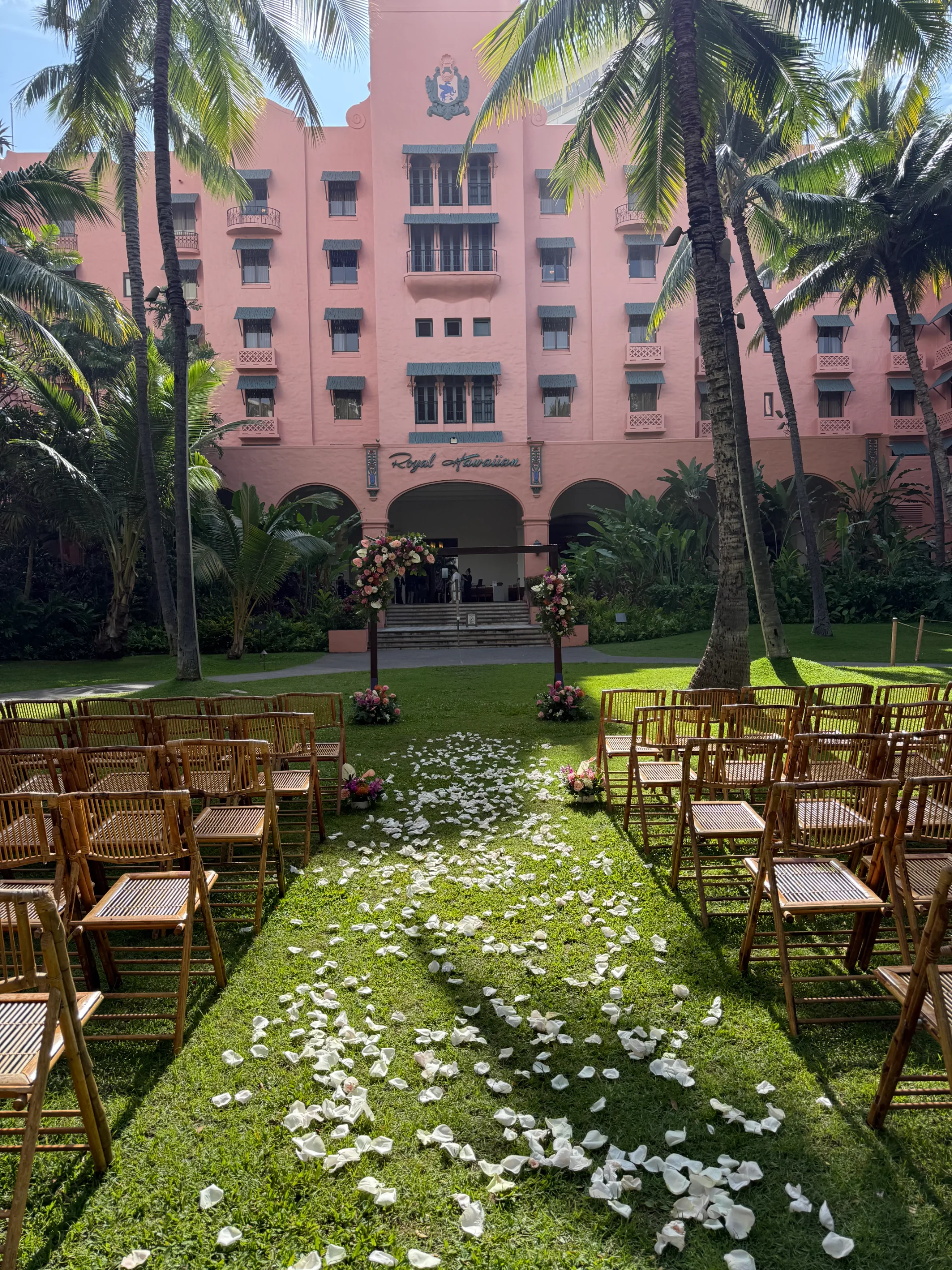 Elegant wedding ceremony setup with bamboo chairs and white rose petals at Royal Hawaiian Hotel, Oʻahu.