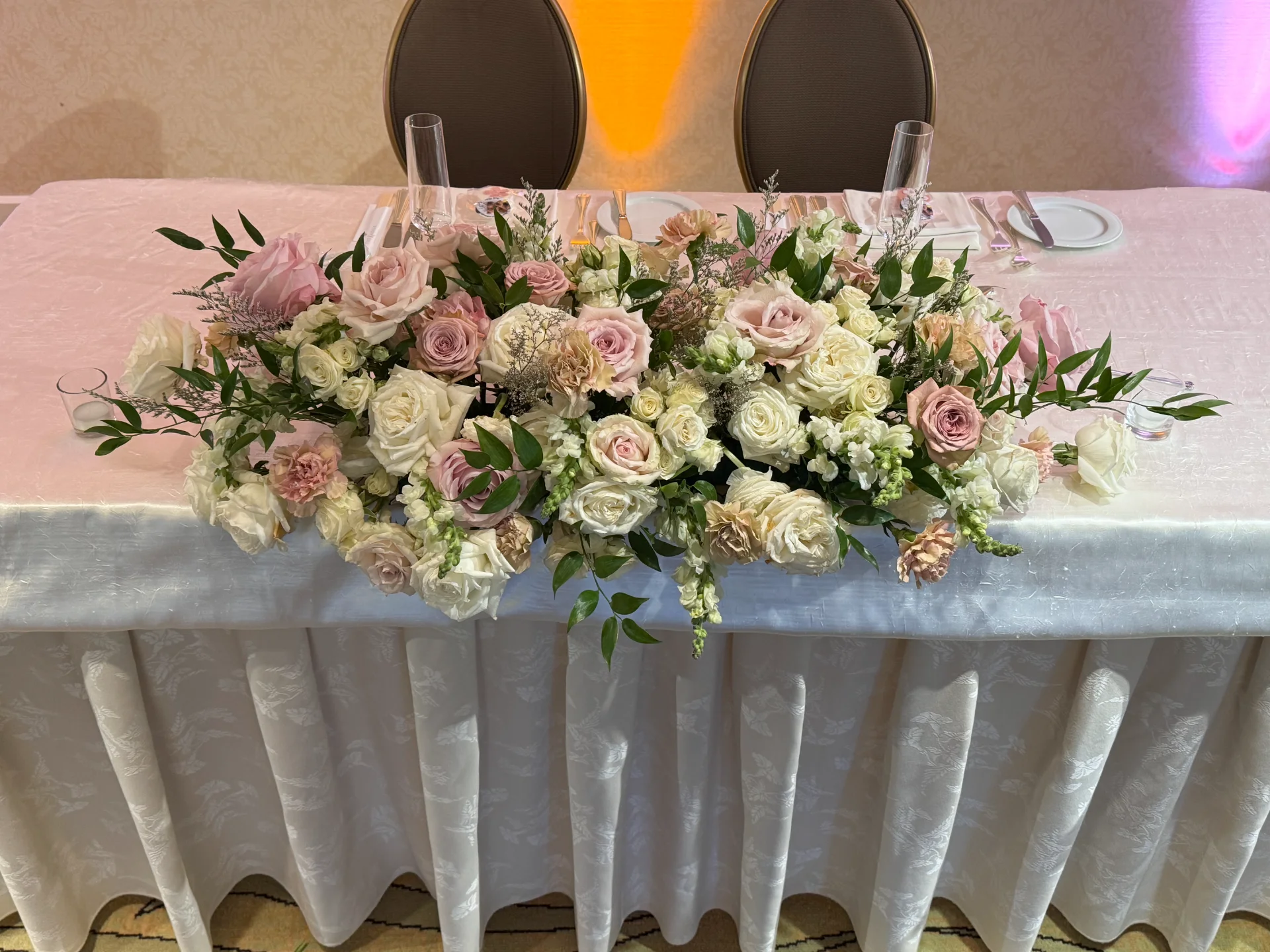 Elegant wedding floral arrangement with blush and ivory roses on a table at a luxury wedding in Oʻahu.