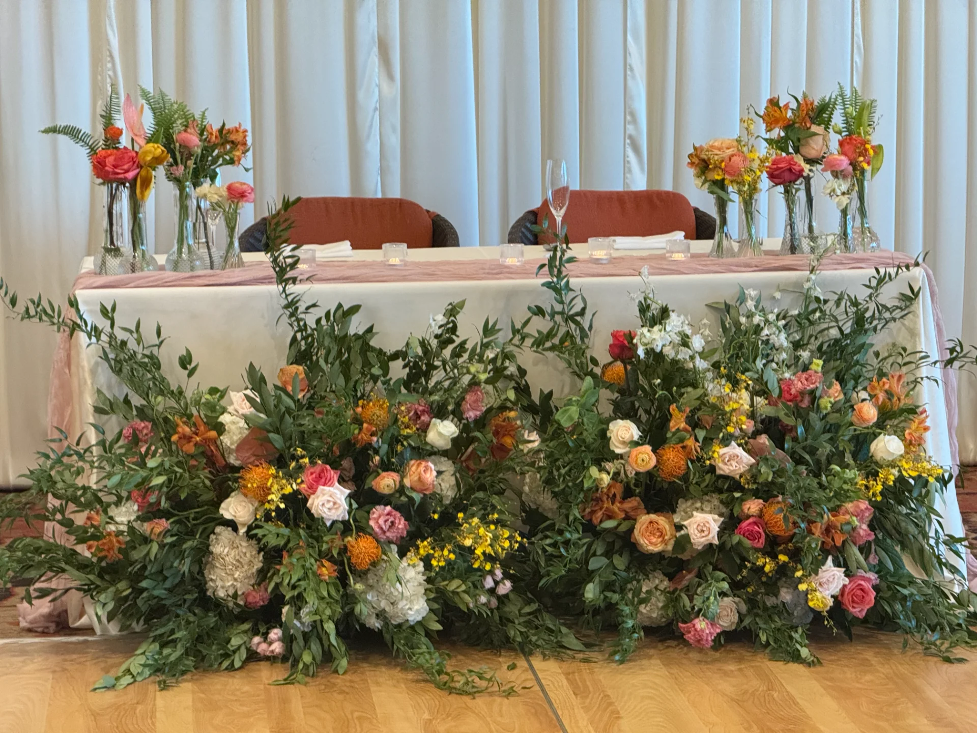 Elegant wedding reception table on Oʻahu adorned with vibrant floral arrangements featuring roses, hydrangeas, and greenery.