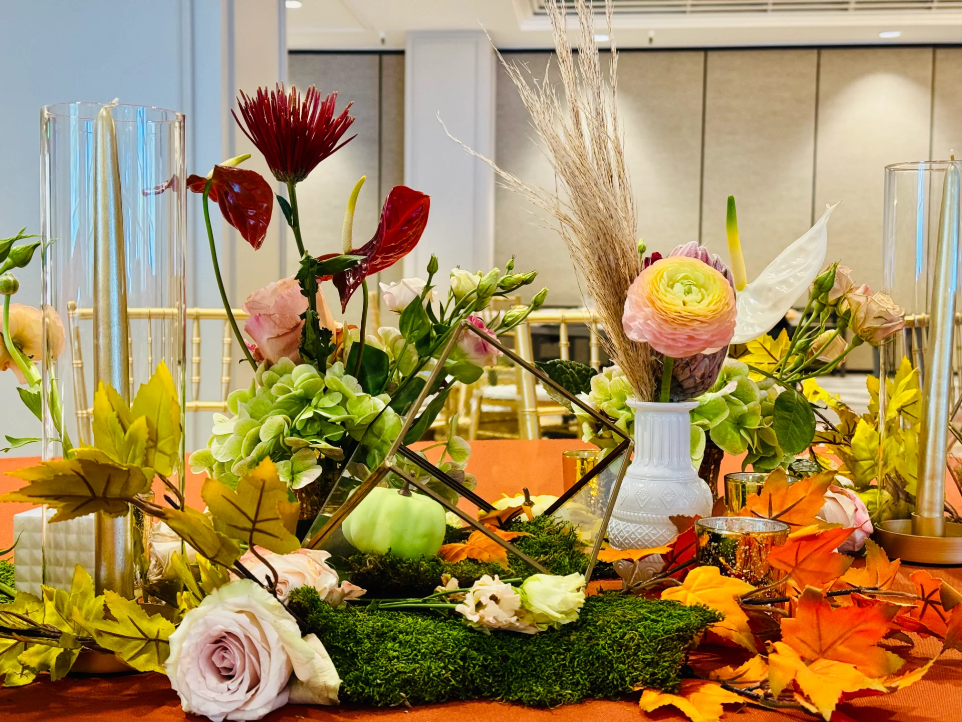 Luxury wedding floral arrangement on Oʻahu with roses, anthuriums, hydrangeas, and autumn leaves on a table.