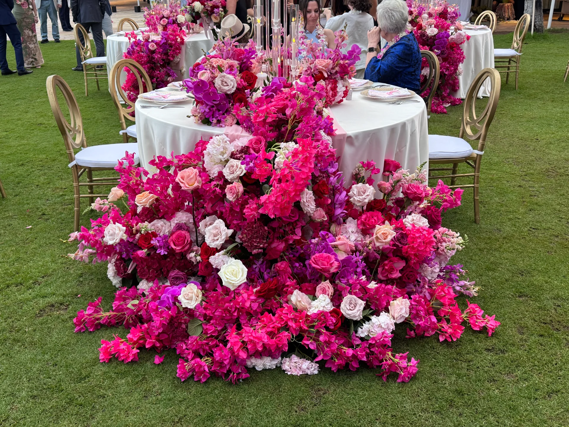 Luxurious wedding reception with vibrant pink and white floral arrangements featuring roses and orchids on Oʻahu.