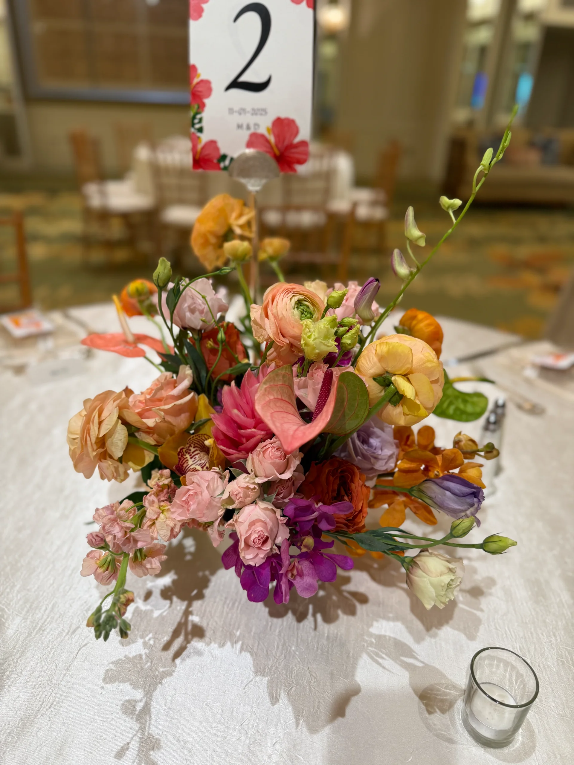 Elegant wedding centerpiece on Oʻahu featuring vibrant roses and anthuriums with rich pink, orange, and purple hues.