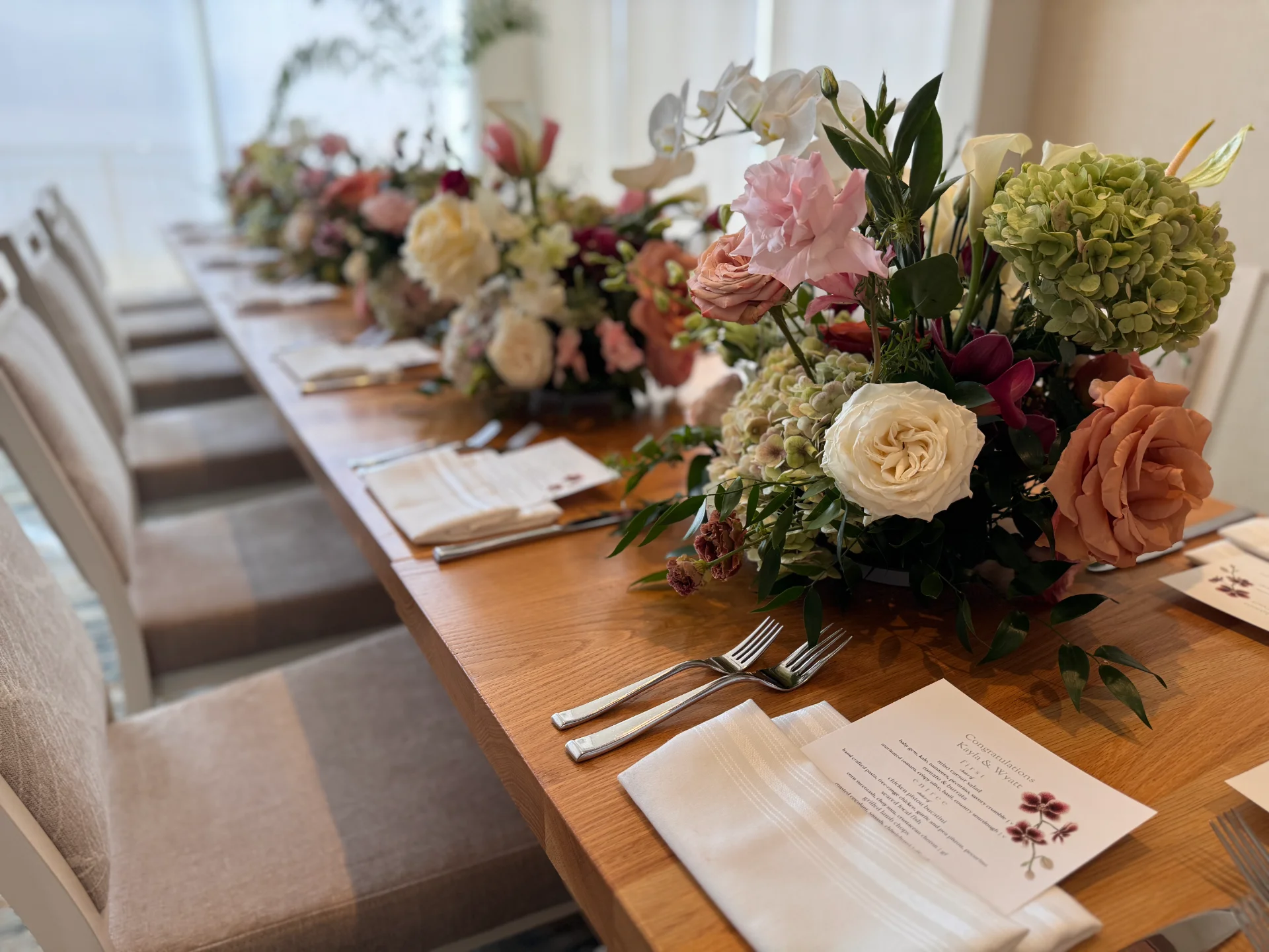 Elegant wedding table with lush floral centerpieces featuring roses, orchids, and hydrangeas in soft pinks and creams on Oʻahu