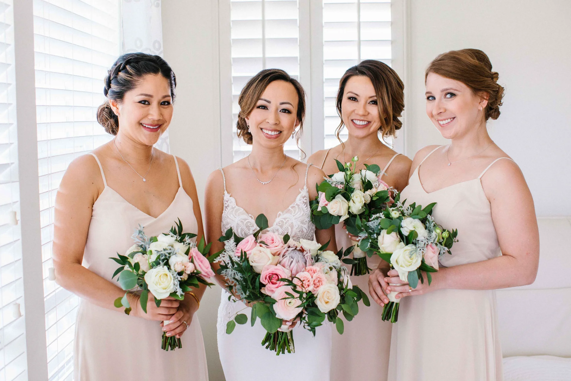 Bridal party with elegant bouquets of white and pink roses at Lanikūhonua Cultural Institute in Hawaii.