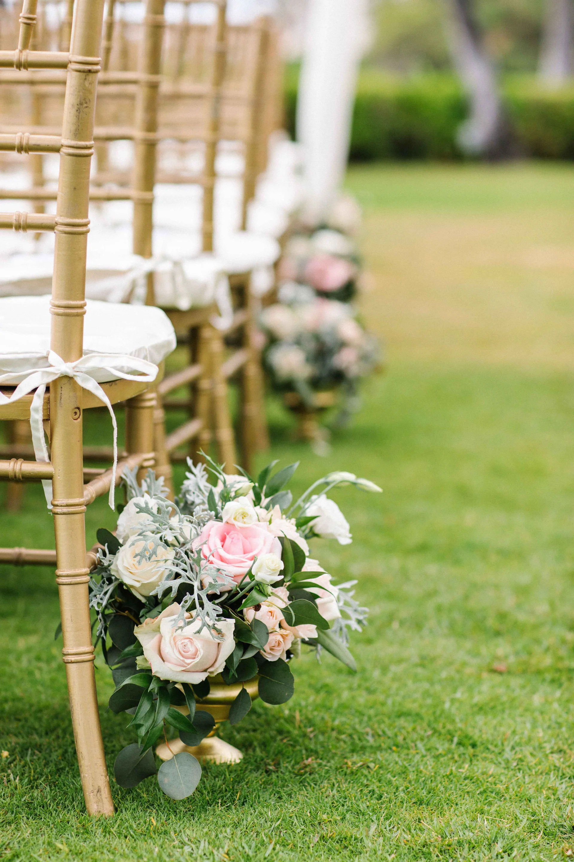 Elegant wedding ceremony with pink and white roses, eucalyptus, and greenery on gold chiavari chairs at Lanikūhonua Cultural Institute, Oʻahu