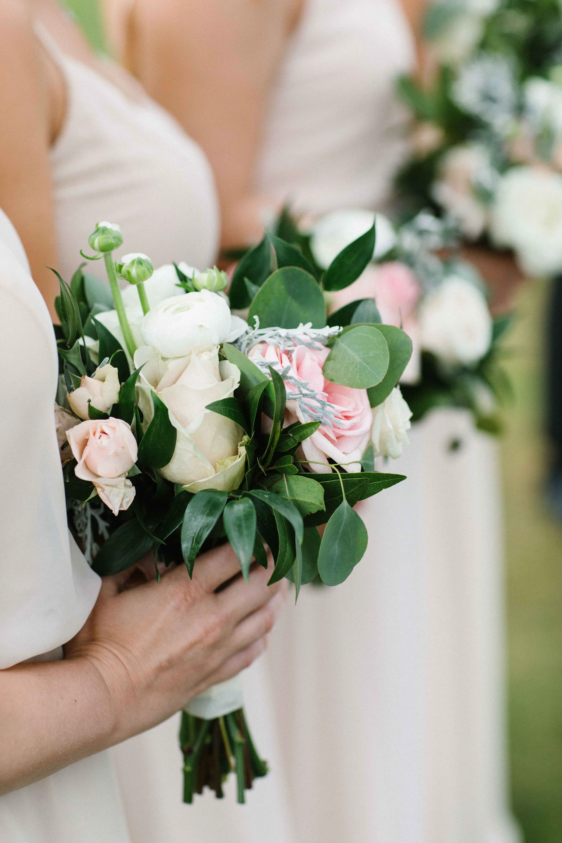 Bridesmaids holding bouquets with white and pink roses, eucalyptus, and greenery at Lanikūhonua Cultural Institute wedding Oʻahu