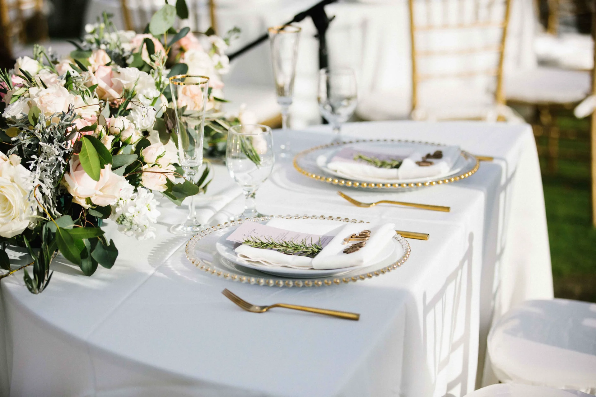 Elegant wedding table setting at Lanikūhonua Cultural Institute with white and blush floral arrangements and gold accents.